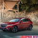 A red Genesis GV70 is parked in front of a sand-dumping apparatus.